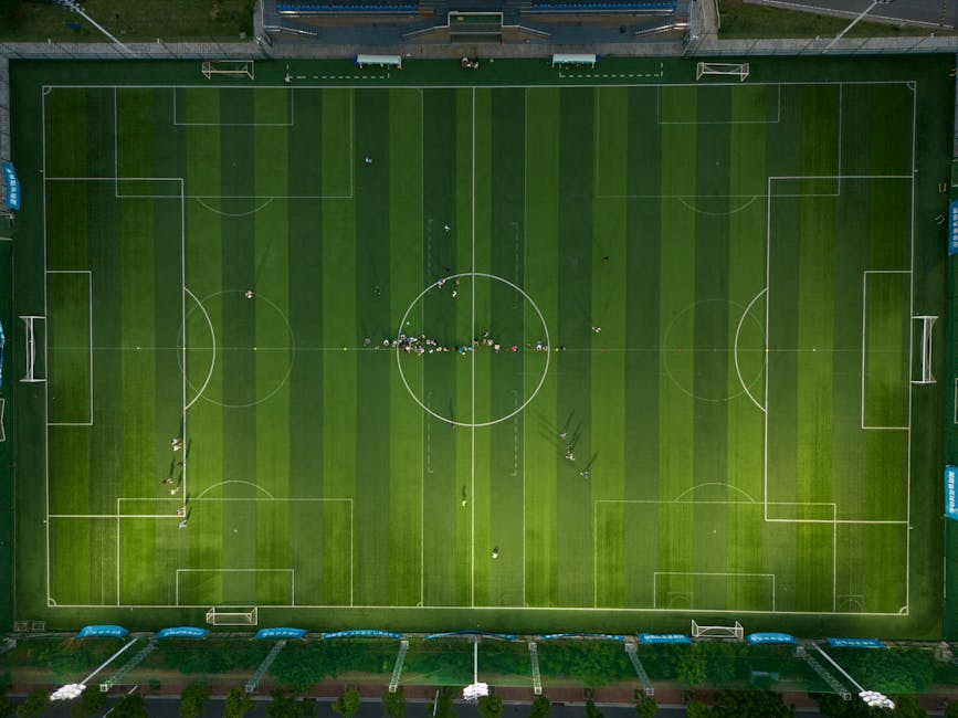 Top-down view of a soccer field with players during daytime.