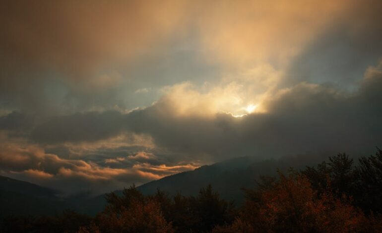 A serene sunset over mountains with dramatic clouds and warm hues.