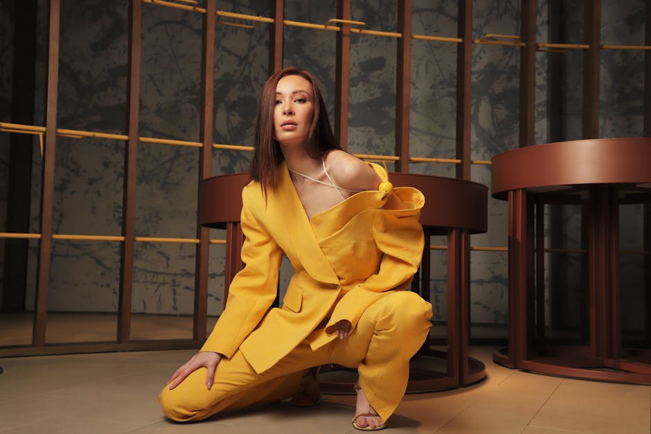 Fashionable woman in a yellow suit posing in a modern indoor setting.
