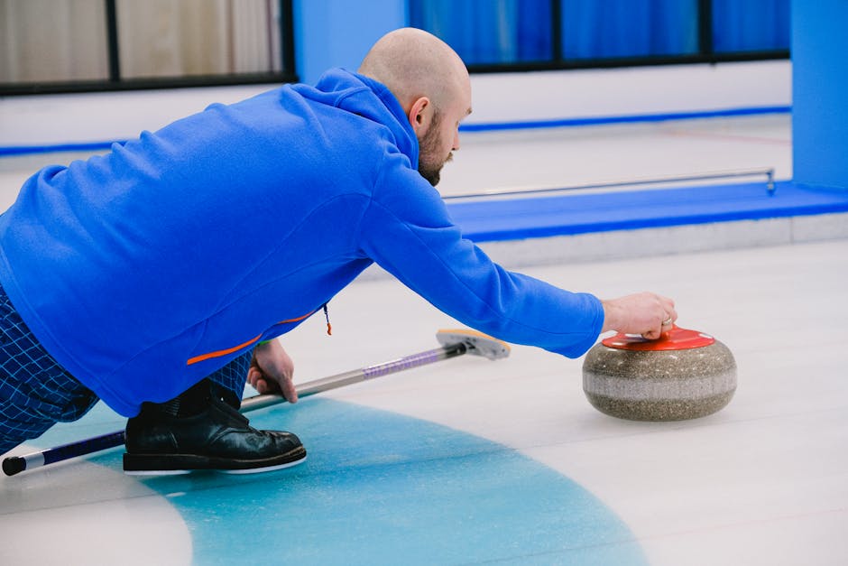 Focused male athlete playing curling indoors, showcasing skill and concentration.