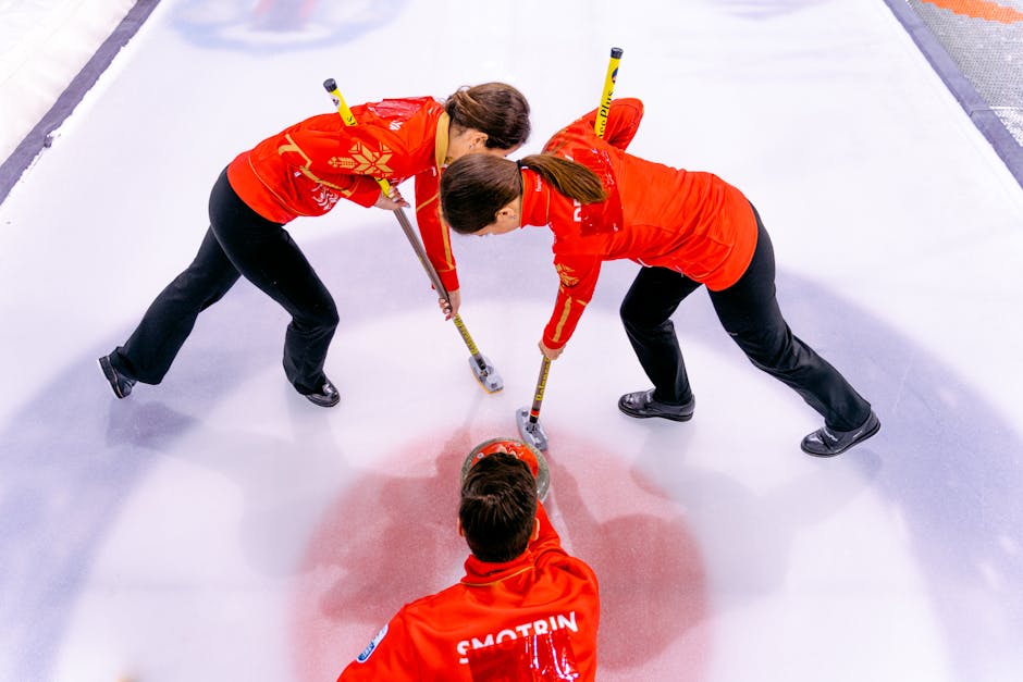 Three curling players sweeping a stone on an indoor ice rink, showcasing teamwork and strategy.
