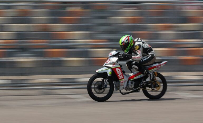 Dynamic shot of a motorcycle racing at high speed on a race track outdoors.