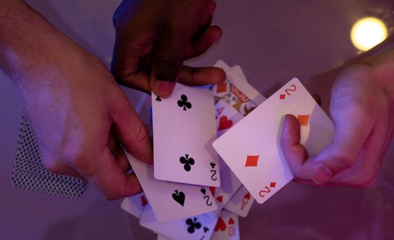 Hands holding playing cards on a glass table with a warm lighting ambience.