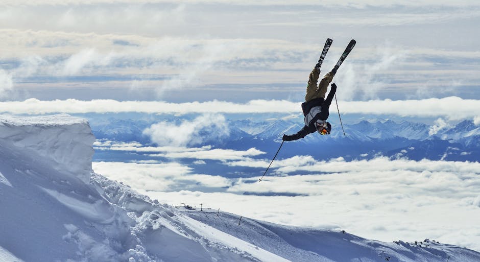 Fit anonymous male athlete in sports wear and skiis with poles demonstrating difficult acrobatic trick in spectacular mounts covered with snow in daylight