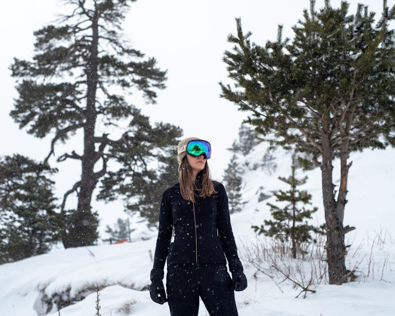 A skier in full gear stands confidently in a snowy forest setting.