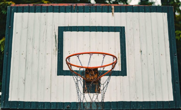 A rustic basketball hoop with a weathered backboard outdoors.