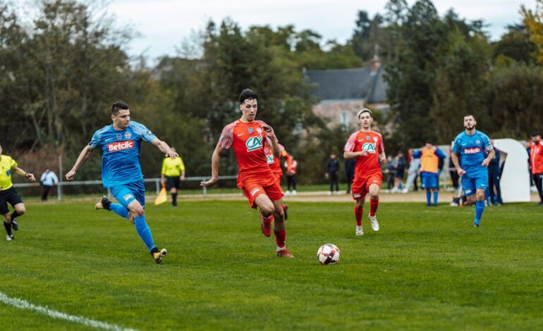 Dynamic football match action captured in France with players in red and blue jerseys.