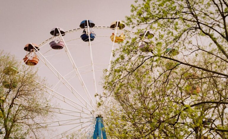 A vibrant ferris wheel rising above green trees during springtime in Ростов-на-Дону, Russia.