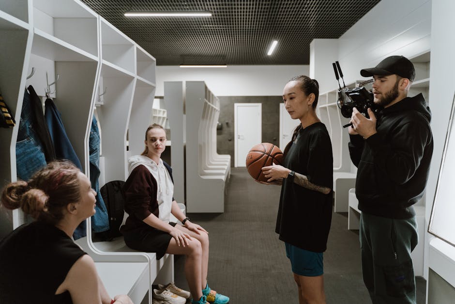 A candid behind-the-scenes look inside a basketball locker room during an interview with athletes and a cameraman.