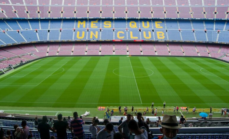 Aerial view of Camp Nou Stadium in Barcelona, showcasing the iconic 'Més Que Un Club' seating in daylight.