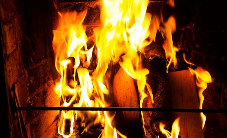 Bright flames consuming firewood in a brick fireplace, radiating warmth and comfort.