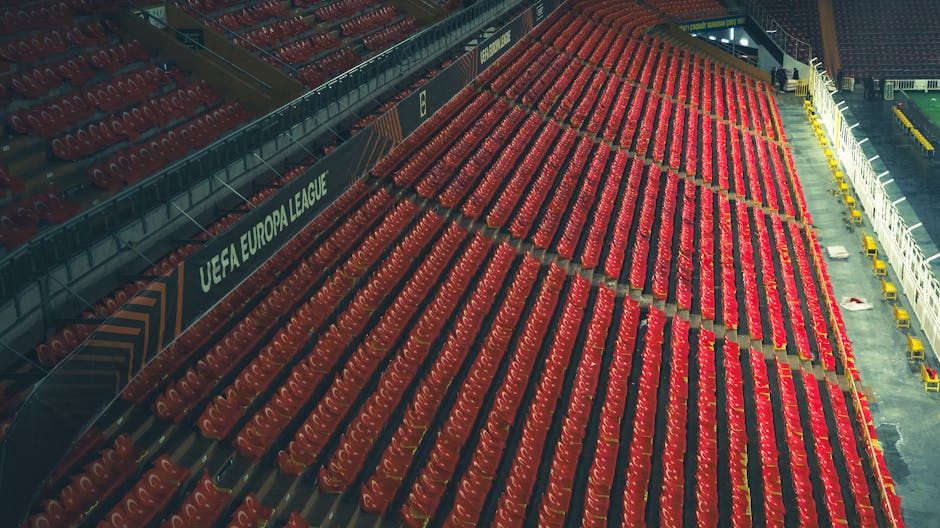 Rows of empty red seats in a UEFA Europa League stadium, captured from above.