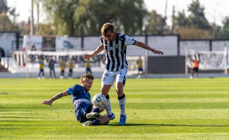 Two soccer players battle for the ball during a competitive outdoor match.