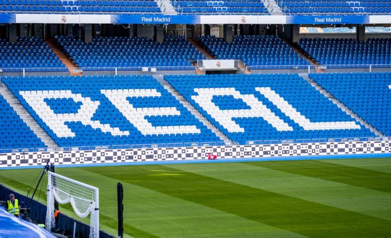 Empty seating area in Real Madrid's stadium with 'REAL' prominently displayed in white.