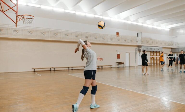 Action shot of a female athlete serving in an indoor volleyball game.