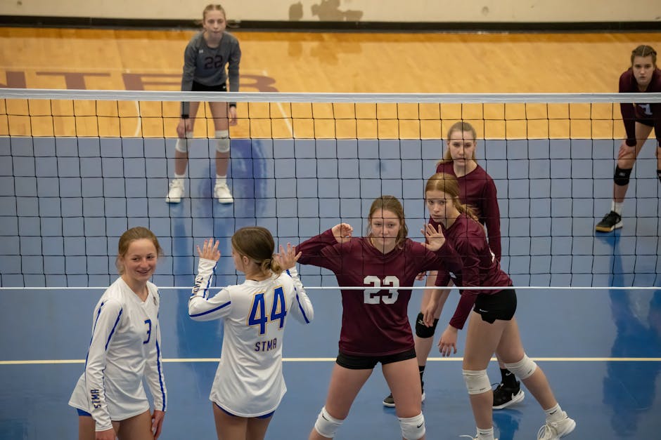 Teen girls playing volleyball indoors in Rochester, MN, showcasing teamwork and competition.