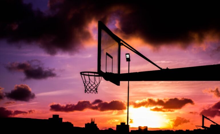 Stunning silhouette of a basketball hoop against a vivid sunset sky with dramatic clouds.