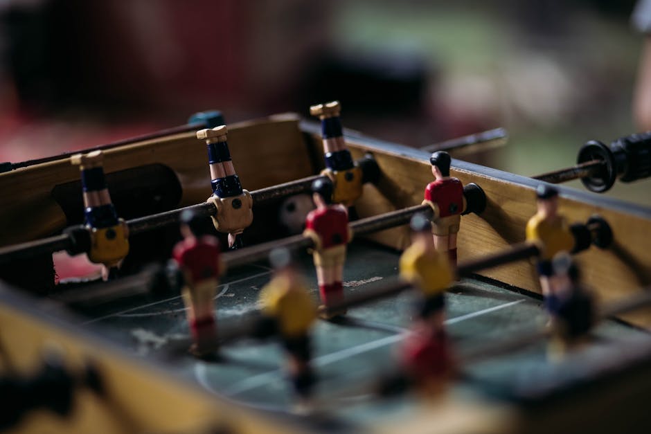 Close-up of a foosball table with miniature soccer players in action.