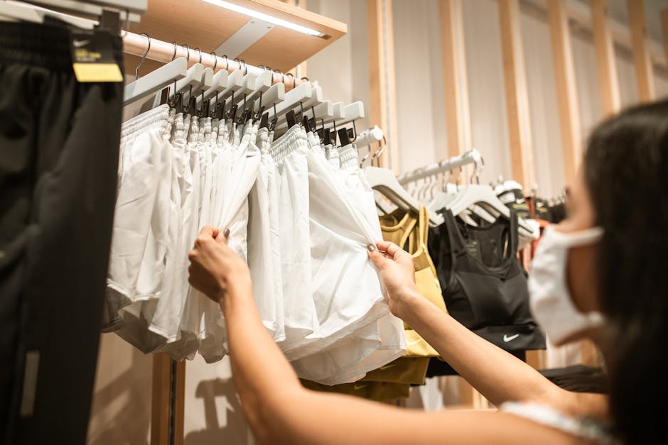 Customer with face mask shopping for workout shorts and activewear indoors.