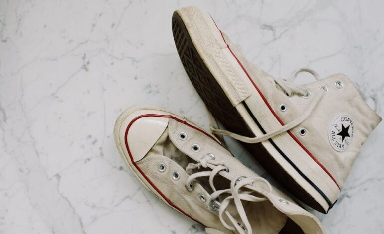 Close-up of worn Converse All-Star sneakers on a marble floor for a vintage fashion style.