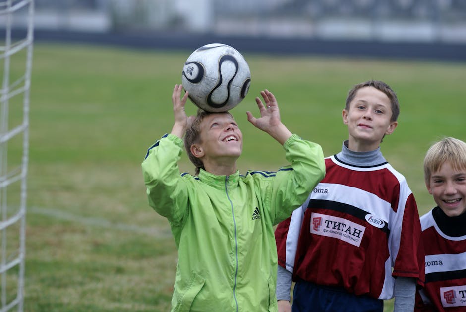 Three young soccer players practicing headers on a soccer field, enjoying their game outdoors.