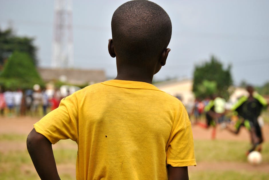 A young boy in a yellow shirt watches a local soccer game in Kpalimé, Togo.