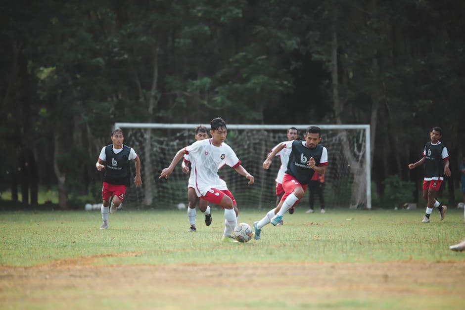 Dynamic action shot of young men playing soccer on a lush outdoor field.
