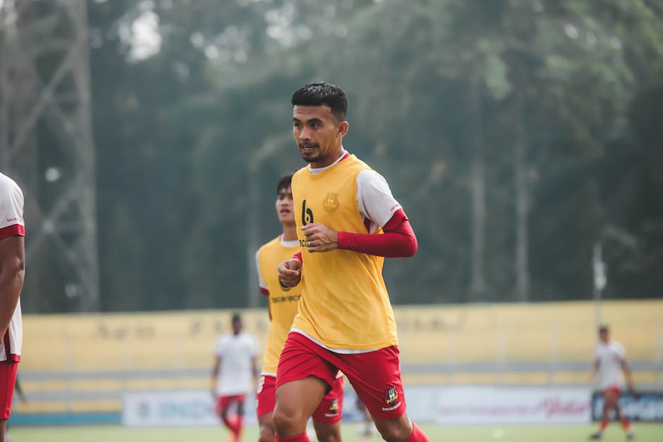 Dynamic shot of a football player in mid-game at an outdoor field, showcasing determination and focus.