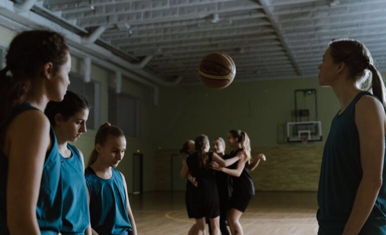 Young female basketball players in a dimly lit indoor court showing emotions.