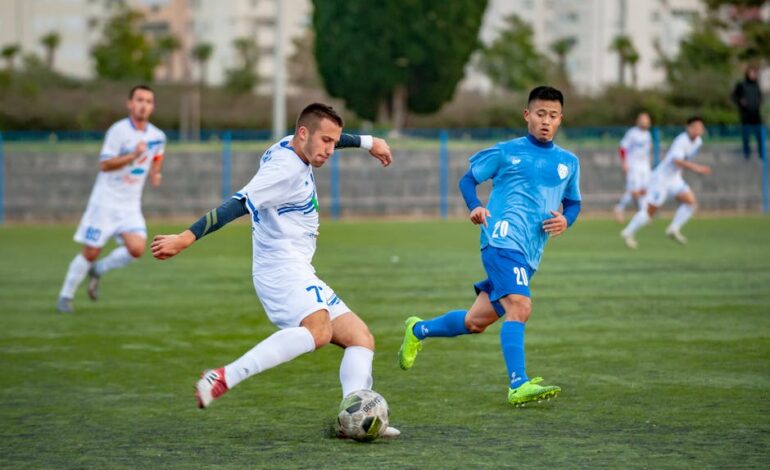 Football players in motion during a competitive soccer match on an outdoor field.