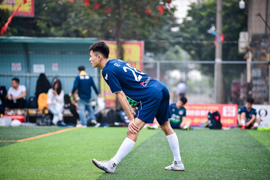 Soccer player stretching on a football field in Hanoi, Vietnam, preparing for a game.