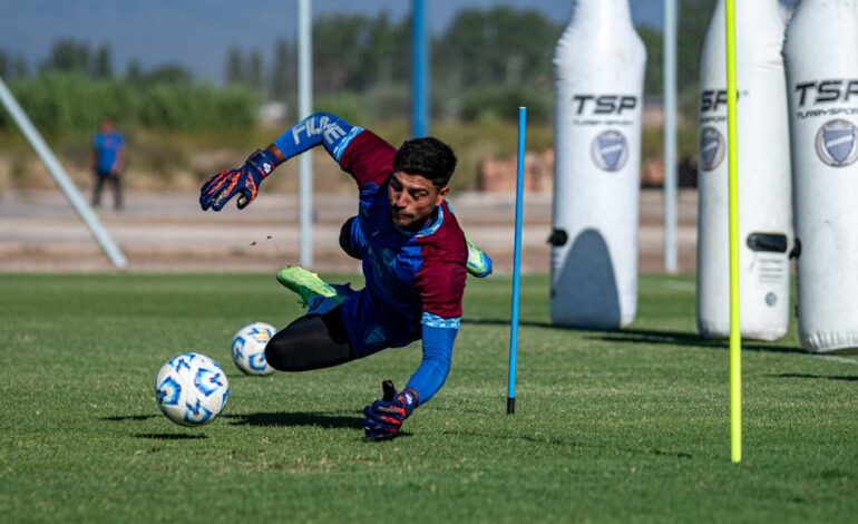 Focused goalkeeper diving to make a save during outdoor soccer training with training dummies.
