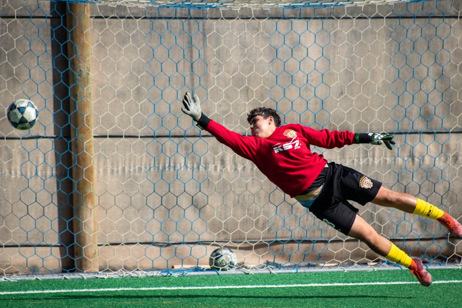 A dynamic shot of a soccer goalkeeper diving to save a ball at a local field in Chile.