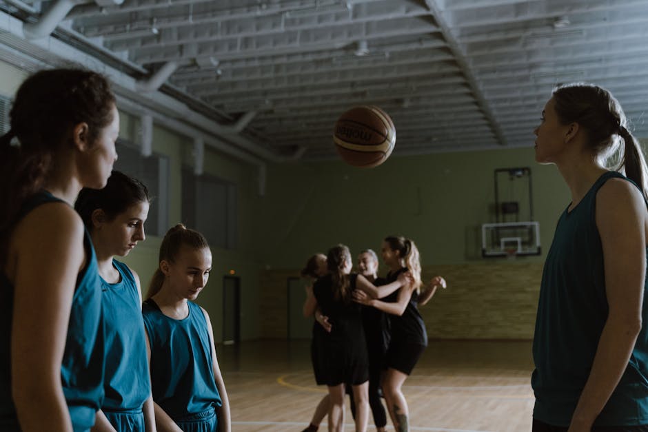 Young female basketball players in a dimly lit indoor court showing emotions.