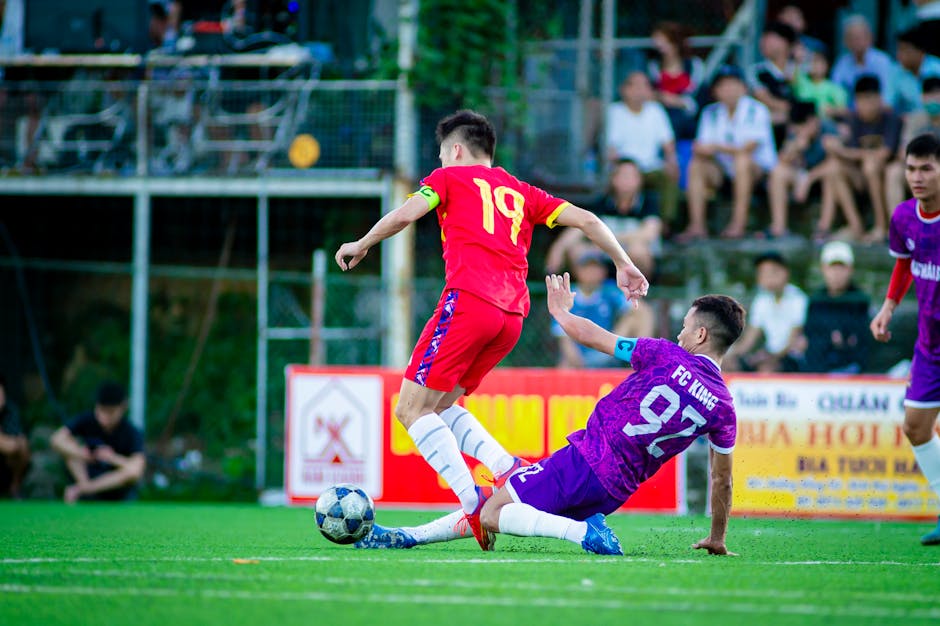 Exciting football match capture with players in action on a sunny day in Hanoi.