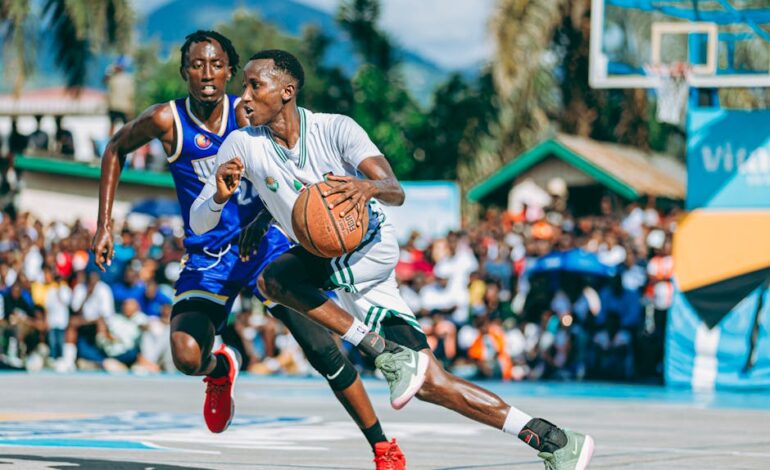 Intense basketball game with two players competing outdoors, surrounded by an excited crowd.