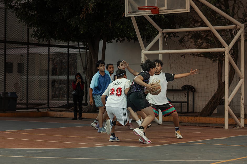 Players engage in a dynamic street basketball game on an outdoor court.