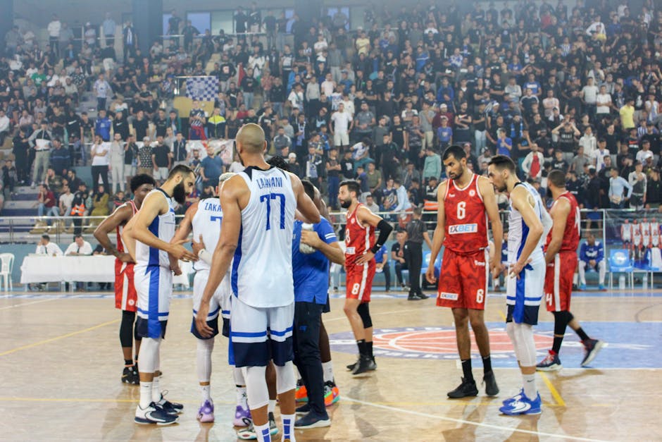 Basketball players in action during a competitive match with a full stadium crowd.