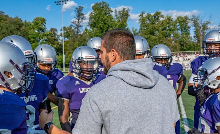 A coach leads a football team huddle during a game outdoors in Columbia.