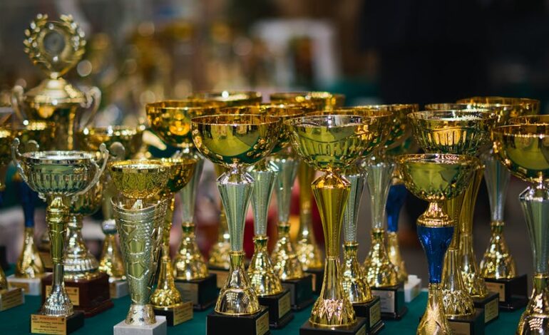 Array of golden trophies on a table, reflecting victory and achievement.