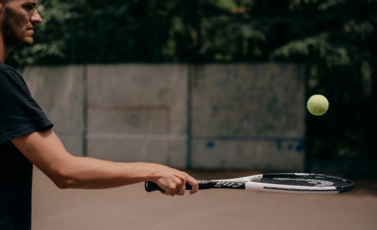 Side view of a male tennis player practicing outdoors, focusing on technique.