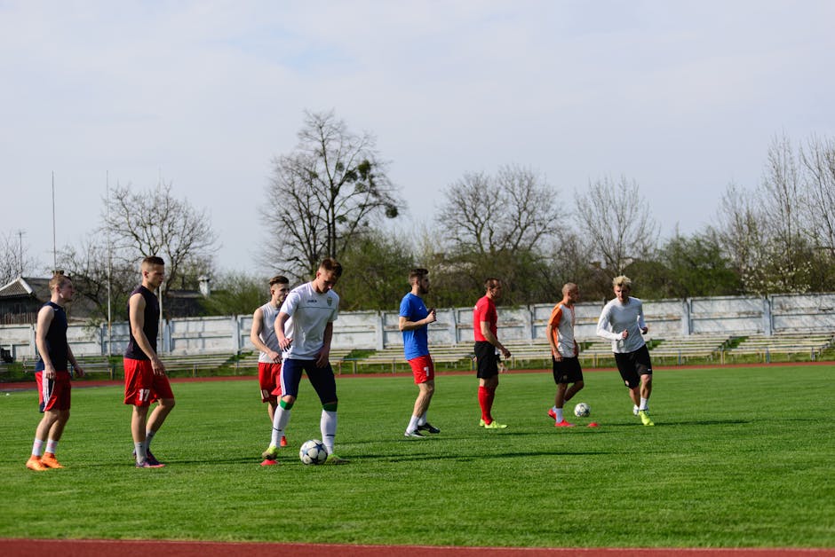 A group of young men practicing football on a lush green field under a bright sky.