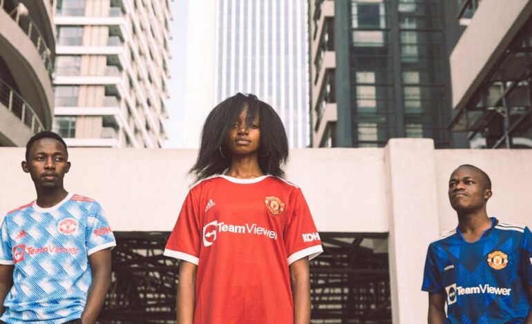 Three young adults in sports jerseys pose confidently in an urban Kenyan setting.
