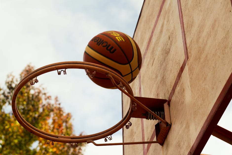 Basketball in motion as it goes through the hoop on an outdoor court.