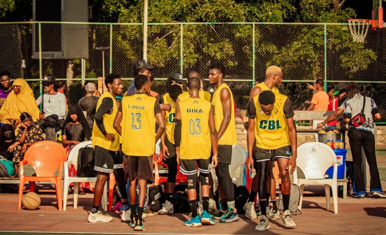 Basketball team huddling on an outdoor court, preparing for a game under the sunny sky.