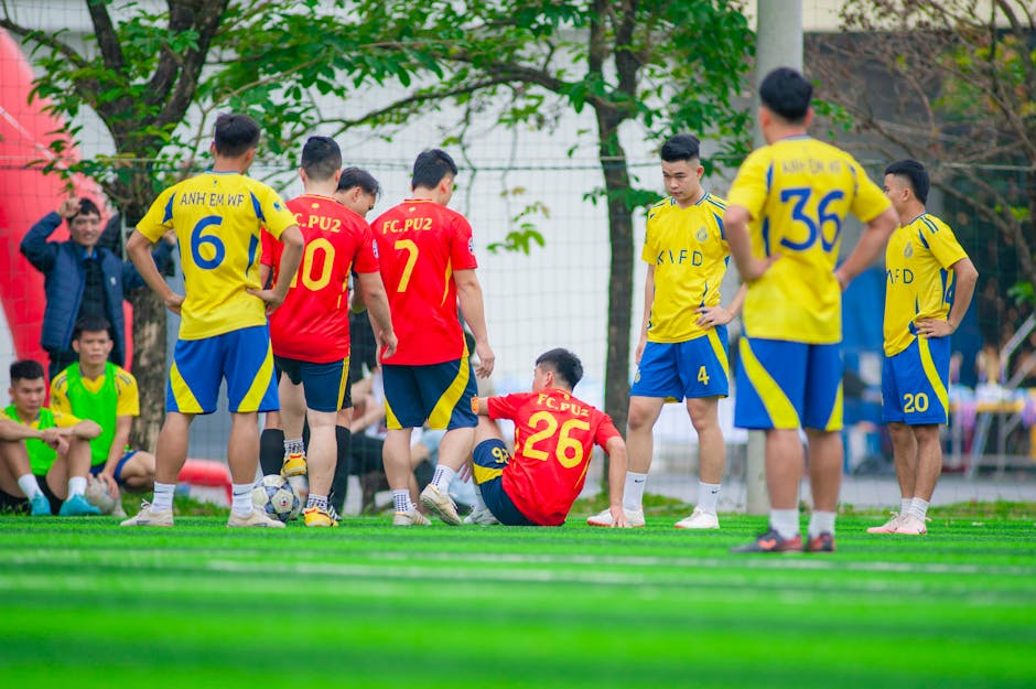 Amateur football match with athletes in Hanoi, Vietnam wearing colorful jerseys.