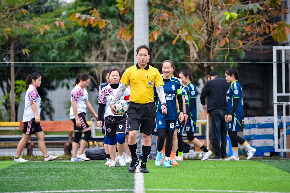 Football referee leading women's teams onto the field in Hanoi, Vietnam.