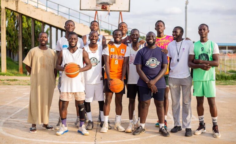 Team of young men posing on an outdoor basketball court for a team photo.