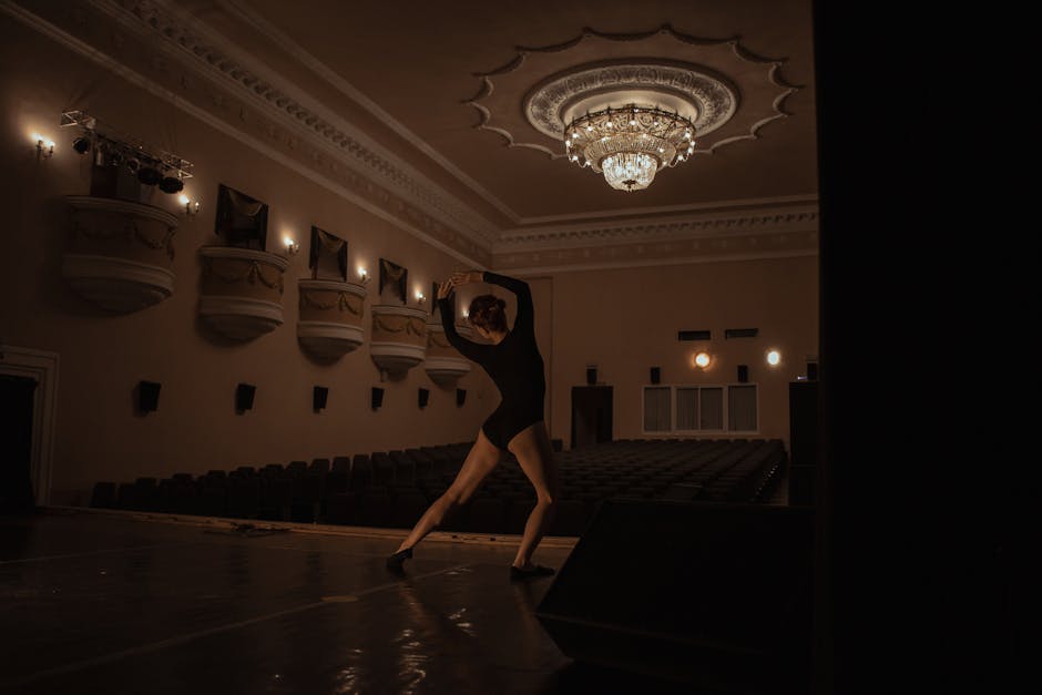 A ballet dancer rehearsing on stage in a beautifully lit theater with classic decor in Moscow.