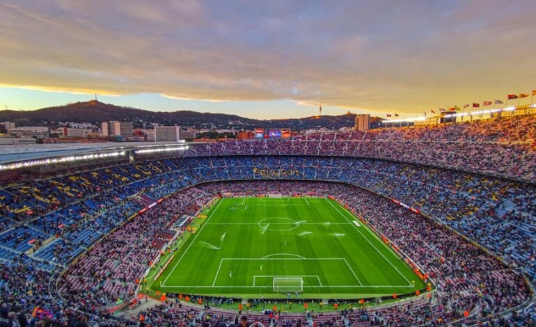 Aerial view of Camp Nou stadium filled with spectators during a football match at sunset in Barcelona, Spain.